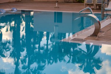 Detail of a swimming pool of a hotel with a reflection of a palm tree, Caleta de Fuste, Fuerteventura, Canary Islands, Spain