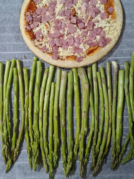 Healthy vs unhealthy food, margarita pizza and green asparagus, top view, ready to be coocked