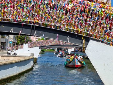 Moliceiro, Aveiro 'lu tipik bir Bask, renkli kurdelelerle dolu bir köprünün altından geçiyor, Aveiro, Portekiz