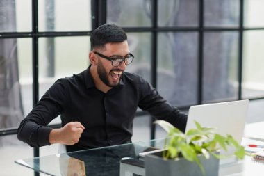 ofiste onun masasında oturan bir laptop ile iş adamı