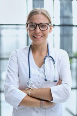 Kendine güvenen kadın doktor beyaz önlük gözlük takıyor.