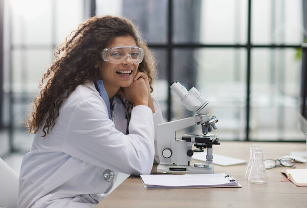 Young woman in biological laboratory. Attractive young female scientis. Scientist using a microscope in a laboratory