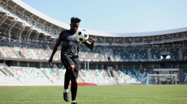 Stadyum sahasında futbol oynayan Afrikalı Amerikalı bir adam..