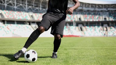 Stadyum sahasında futbol oynayan Afrikalı Amerikalı bir adam..