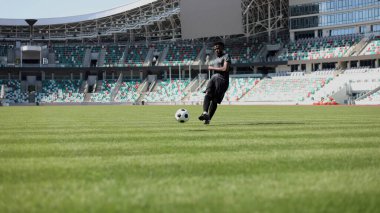 Stadyum sahasında futbol oynayan Afrikalı Amerikalı bir adam..