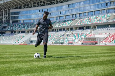 Stadyum sahasında futbol oynayan Afrikalı Amerikalı bir adam. Bir adam elinde futbol topuyla sahada koşuyor..
