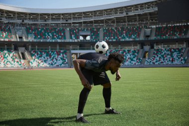 Bir futbolcu topu sırtında tutarak antrenman yapıyor. Afrika kökenli Amerikalı futbolcu.