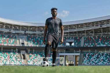 Futbol oyuncularının ayakları stadyumda futbol topuna basıyor.