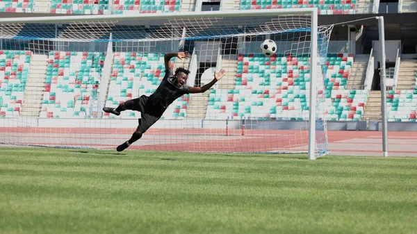 Football goalkeeper catches the ball in the stadium. game concept