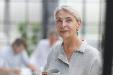 close-up mature woman holding a cup in the office.