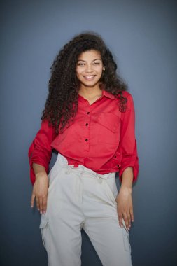 Gri duvar arkasında yalnız poz veren mutlu genç iş kadını..