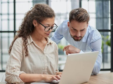 Meslektaşlar bir dizüstü bilgisayar kullanarak belgeleri kontrol ederler. Bir adam ve bir kadın birlikte oturmuş laptopa bakıyorlar. iş kavramı