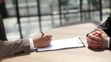 İş adamlarının elleri sözleşme, yasal belgeler veya başvuru formunun nerede imzalanacağına işaret ediyor.
