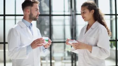 Portrait of young medical doctors looking camera with pack of pills