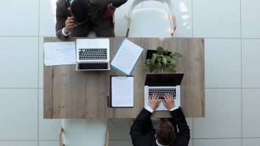 İki iş adamı bir sandalyede oturuyor ve dizüstü bilgisayardan bir şeyler izliyorlar.