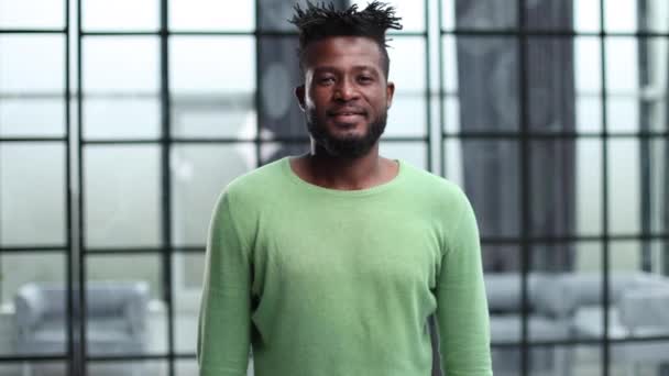 緑のセーターに身を包んだアフリカ系アメリカ人 事務所に立つ — ストック動画