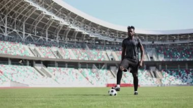 Genç Afrikalı Amerikalı adam stadyumda duruyor ve top maça hazırlanıyor.