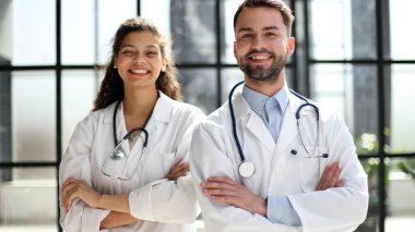 Kadın doktor ve erkek doktor hastanenin lobisinde duruyorlar.