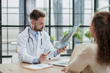 Doktor muayenehanesinde röntgene bakan yetenekli genç bir erkek doktor.