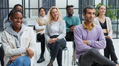 Konferans odasındaki sandalyelerde oturan çeşitli gençler.