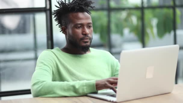 若いアフリカ系アメリカ人の男性がノートパソコンのキーボードで — ストック動画