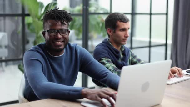 アフリカ系白人の同僚はPc企業のアプリを使いメンターは新しい従業員にインターンシップやチームワークの概念を教え — ストック動画