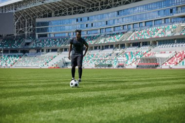 Stadyum sahasında futbol oynayan Afrikalı Amerikalı bir adam..
