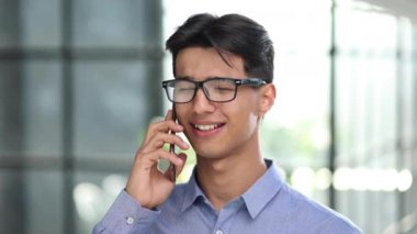 Bir iş adamı, modern bir ofisin lobisinde dururken bir telefon görüşmesi yapar. yakın plan