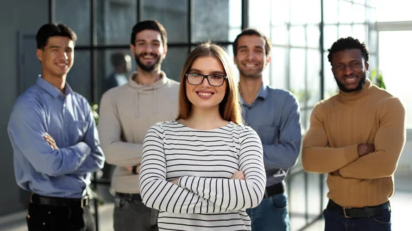 İş kadını ve meslektaşlarının portresi ofiste kollarını kavuşturmuş duruyor.