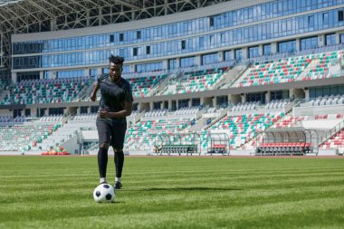 Stadyum sahasında futbol oynayan Afrikalı Amerikalı bir adam..