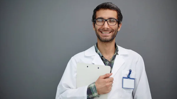 Portret Pozytywnego Lekarza Pozowanie Uśmiech Kamery Szarym Tle Studio — Zdjęcie stockowe