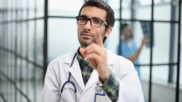 病院の廊下に立っている間あなたを指差している白いコートの中の気配りのある医者 — ストック写真