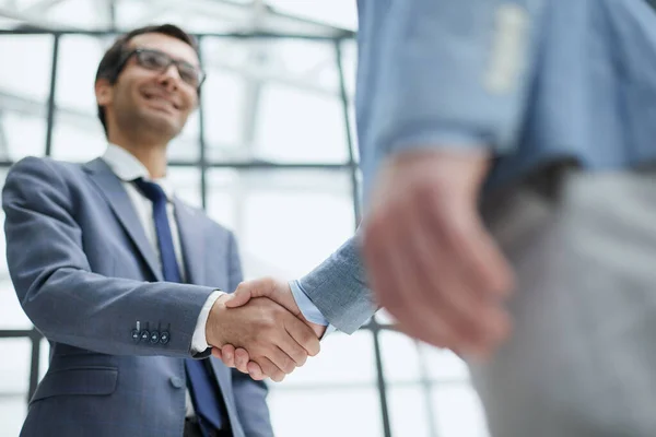 stock image Businessmen shake hands, standing near a large office window
