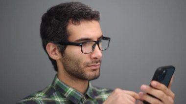 Pozitif genç erkek akıllı telefon tutuyor, sosyal ağda arkadaşlarıyla sohbet ediyor.