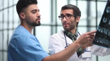 Doktorlar ve stajyer bir hastanın röntgenini inceliyor. Beyin aktivitelerinin ve bilim adamlarının MR taramaları.