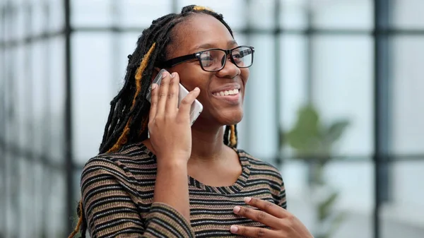 Close-up portrait of a black employee in glasses talking on the phone