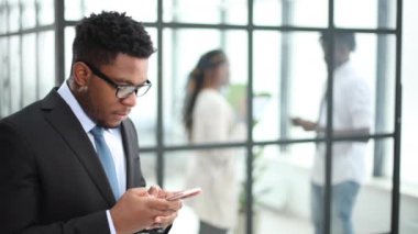 Ofiste cep telefonuyla konuşan gülümseyen Afrikalı genç adamın yakın plan portresi.