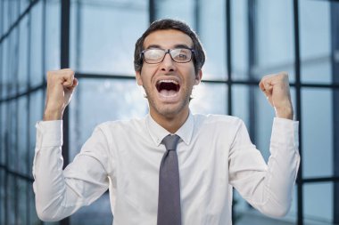 Milenyum ofis çalışanı koridorda yumruklarını sıkarak durarak kariyerinin ilerlemesini kutluyor.