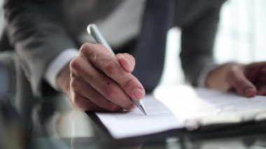 Ofis masasında oturan bir işadamı imzaya odaklı bir sözleşme imzalıyor..