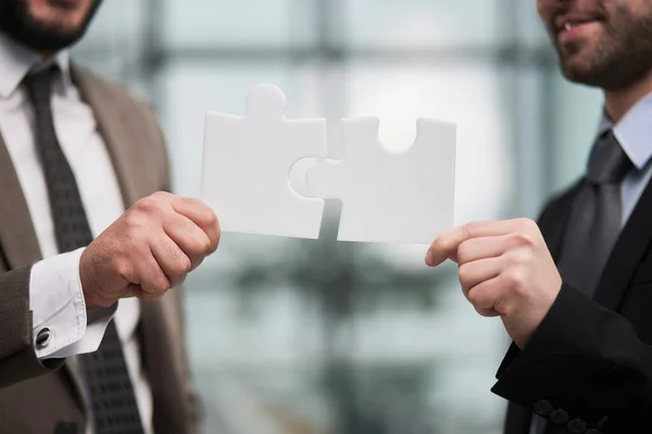 Stock image Working together to put things together. two unrecognizable businesspeople fitting puzzle pieces together in studio