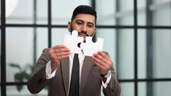Business puzzle, strategy and marketing. Businessman shows silver pieces of the puzzle