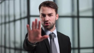 İş adamı ve jest konusu, siyah takım elbiseli ve beyaz gömlekli bir adam el hareketini durdurma ya da tutma hareketi yapıyor.