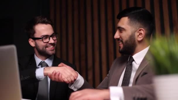 会社のテーブルで会うと二人の若い男が笑って握手 — ストック動画