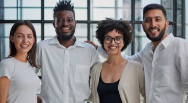 Başarılı yaratıcı iş ekibinin portresi kameraya bakıyor ve gülümsüyor. Başlangıçta çeşitli iş adamları bir arada duruyorlar.