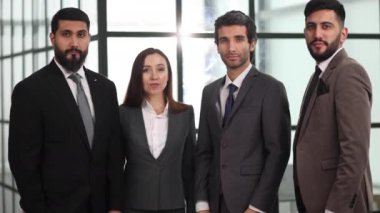 Takım başarılı çalışanları modern ofiste birlikte poz veriyorlar. Takım çalışması, işbirliği, ortaklık
