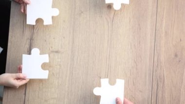 Çeşitli ekip üyeleri yapboz yapıyor, siyah ve beyaz meslektaşlardan oluşan çok ırklı bir grup birbirini takip ediyor.