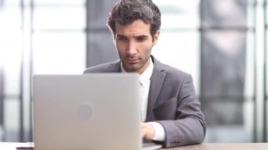 Ofis içinde başarılı bir iş adamı, iş yerinde evraklar ve dizüstü bilgisayarla çalışan takım elbiseli bir adam.