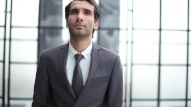 Profil görünümlü genç bir iş adamı, ofiste el pençe divan duruyor.
