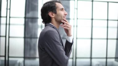 Profil görünümlü genç bir iş adamı, ofiste el pençe divan duruyor.