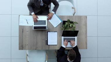 İki iş adamı bir sandalyede oturuyor ve dizüstü bilgisayardan bir şeyler izliyorlar.